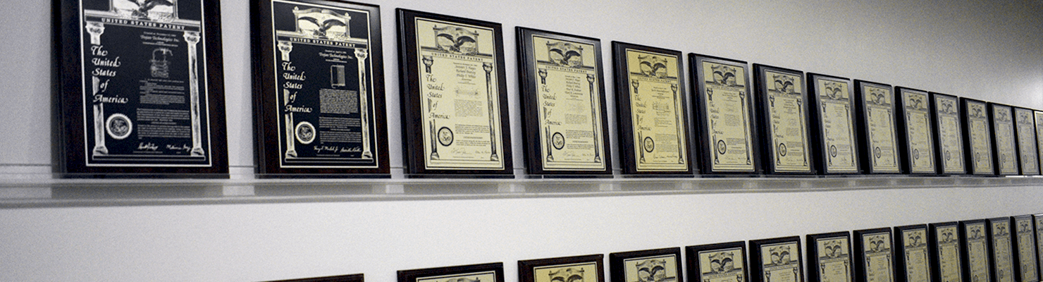 Patents belonging to Trojan Technologies displayed on a wall.